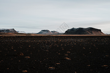 山峰黄昏冰岛的S海滩鹅卵石火山观光旅游海岸地形生态旅游风景山峰日落背景