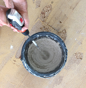 男人把灰水泥混在一起 在桶子里瓦工建筑材料砂浆石膏地面工艺螺旋投掷工人建筑图片
