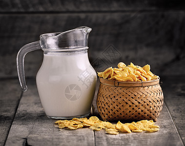 篮子中的玉米片和木制桌上的牛奶杯图片
