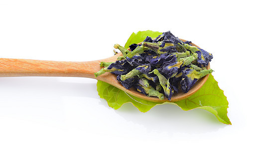 白色背景的木勺中的干豆花健康蝴蝶医疗绿色蓝色叶子草本植物草本紫色染料图片