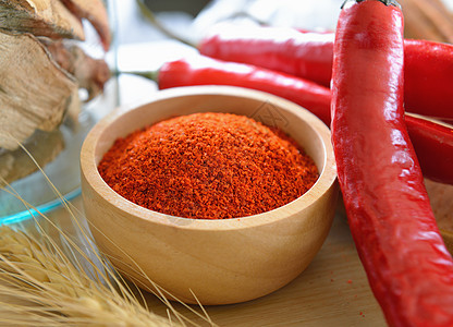 木碗中的辣椒粉末香料厨房糖果食物木头地面白色红色图片