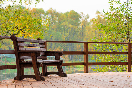 在秋天公园湖边的一座桥上坐木林长凳图片