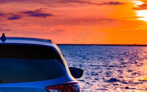 日落时分 蓝色紧凑型 SUV 车停在海边的水泥路上 采用运动和现代设计 环保技术 电动汽车技术和业务 混合动力汽车和汽车奢华杂交背景图片