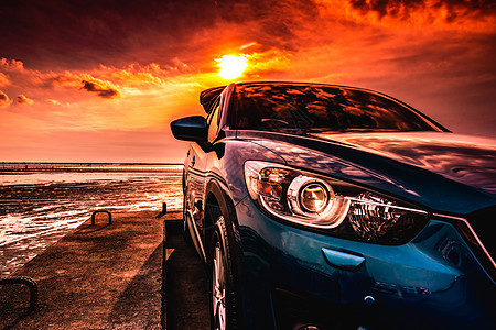 蓝色紧凑型 SUV 汽车 具有运动 现代和豪华的设计 日落时分停在海边的水泥路上 漂亮的混合动力汽车前视图 充满信心地驾驶 在海图片