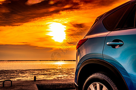 蓝紧凑的SUV车 有运动和现代设计 停在日落时海上水泥路上 环保技术 商业成功概念 蓝色SUV车门带有把手图片