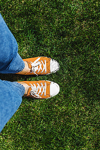 绿色草地上的老黄色脚鞋 从上面看运动鞋生活衣服自由青少年蓝色墙纸成人姿势牛仔裤图片