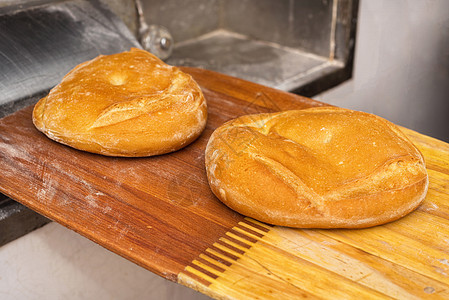 面包刚从烤炉里出来 新鲜烘烤面包生产手工食物烹饪桌子火炉木头团体店铺工厂图片