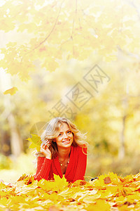 女人躺在秋叶上乐趣喜悦幸福红色微笑快乐金发女性金子橙子图片