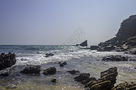 在印度洋 果阿 印度海湾的海海滩 蓝天下碧绿的大海波涛 岩石海岸线终止于海边和山脉 夕阳西下 海岸线上乱石碧波海滩编队岩岸悬崖风背景图片