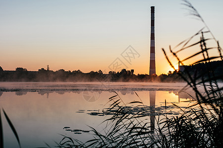 日出在湖上反射日落橙子蓝色太阳钓鱼烟囱工厂薄雾树木图片