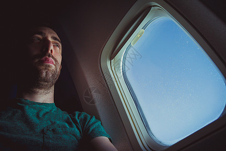 坐在一架飞机窗边的膝盖人座椅上图片