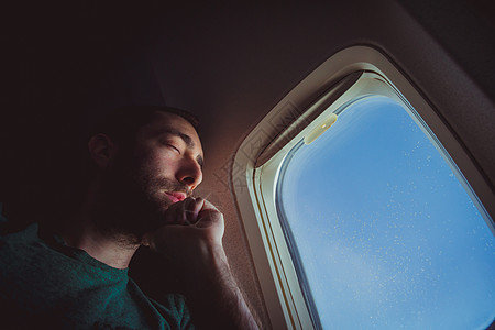 年轻人在飞机上休息和睡着飞行乘客低角度男性睡眠座位旅行商业游客成人背景