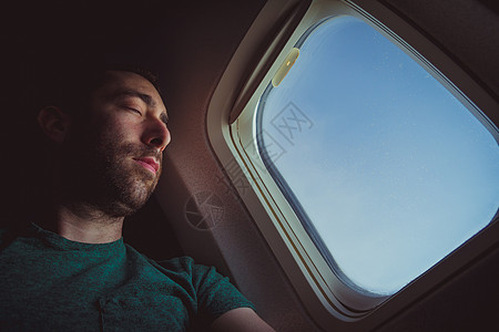 年轻人在飞机上休息和睡着睡眠低角度航班男性男人窗户旅行飞行乘客座位图片