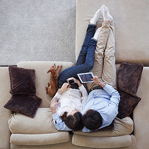 使用平板牌上的一对夫妇夫妻互联网幸福微笑电脑宠物沙发男人长椅恋人图片