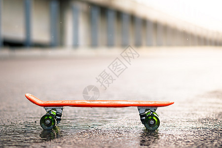雨中湿道上的橙色滑板贴近图片