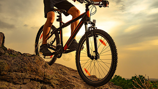 赛车手骑着山上摩托 在日落的岩石下沉 极端运动和概念下坡踪迹车轮娱乐自行车冒险头盔山地车耐力赛成人图片
