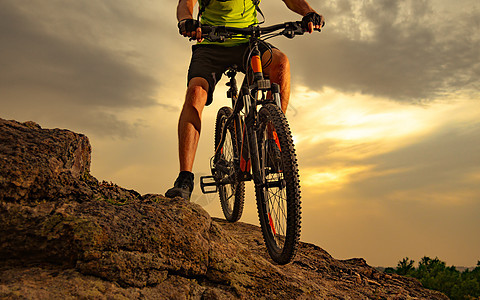 Enduro 自行车手在日落时分在岩石小径上骑山地自行车 自行车特写 积极的生活方式概念图片