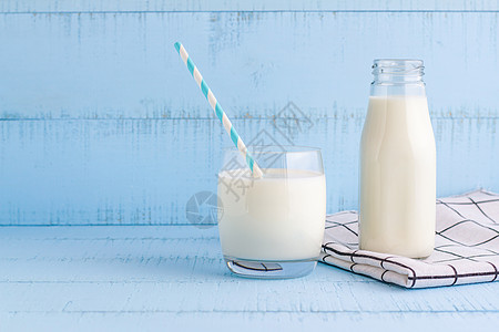 一瓶酒和一杯蓝色木本底的牛奶营养稻草食物桌子瓶子早餐白色奶制品奶油玻璃图片