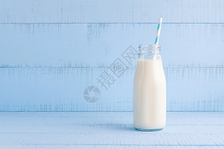 一瓶蓝木本底的牛奶奶制品桌子稻草早餐白色食物奶油瓶子玻璃营养图片