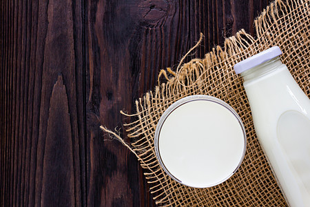 酒瓶和一杯牛奶放在木制背景上白色奶油桌子早餐奶制品玻璃营养食物背景图片