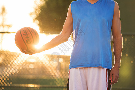 日落时站在操场上玩球的运动员手球手活动身体太阳篮子游戏锻炼娱乐行动篮球运动图片