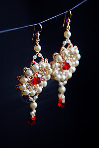 手工制作的饰品由宏中的珠子制成 白色珠子的耳环 石头制成的耳环 漂亮的装饰品 红色珠子的耳环 黑色背景上的装饰品艺术首饰礼物宝石图片
