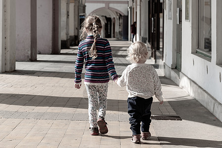 两个年幼的孩子手牵着手走在老城的拱廊街上 亲情友情主题公园教育花园朋友们童年姐姐女孩夫妻朋友学校图片