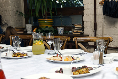 餐厅的桌子上展示了带食物的餐饮午餐海鲜玻璃椅子叶子婚礼环境庆典派对银器图片