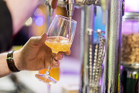 酒保把啤酒倒在玻璃杯里 浅色的 dof 有选择性的焦点饮料草稿餐厅俱乐部男人金属派对酒精夜店柜台图片