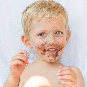 孩子笑着带着肮脏的巧克力 面贴紧了图片