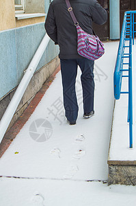 一名白头发老年病人在为残疾人铺上雪盖的坡道上硬爬 留下积雪痕迹保健卫生机动性背光车轮自由公园成人残障男性图片