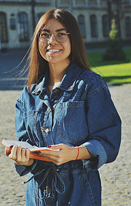 身着牛仔套装的学生站在大学的领土上女孩学校教育夹克运动鞋女性快乐成人眼镜帽子图片