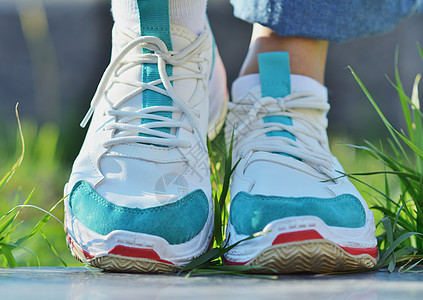 穿着运动鞋的女孩站在草地上鞋带运动学生造型青菜季节牛仔裤领带花边女性图片