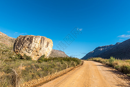 阿尔及利亚通往Dwarsrivier公路的一块巨石旅游农村岩石泥路衬套灌木荒野远景风景旅行图片