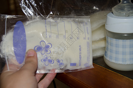 将冷冻的母乳放在储存袋中的妇女手掌和装有新鲜鲜乳制品的婴儿瓶子牛奶库存饮料液体护理母亲塑料营养新生妈妈图片