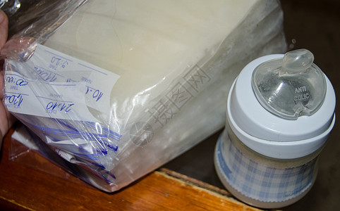 储存袋和婴儿瓶中的冷冻母乳 木制桌上配有新鲜的鲜乳奶图片