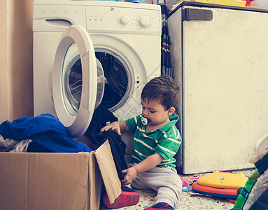 一岁半男婴把衣服放进洗衣机婴儿洗衣店主妇器具推杆加载垫圈女性白色房子图片