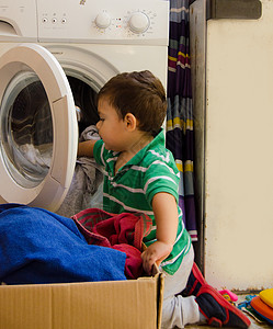 一岁半男婴把衣服放进洗衣机房子母亲推杆主妇洗衣店白色家务加载乐趣女性图片