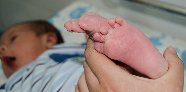 母亲按摩新生儿小婴儿的脚松动父母新生女孩母性孩子脚跟脚趾说谎保健按摩师图片