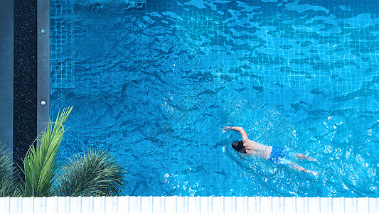 青年男子游泳的泳池顶视图角度床垫女士蓝色高架奢华女性闲暇棕褐色比基尼旅行图片