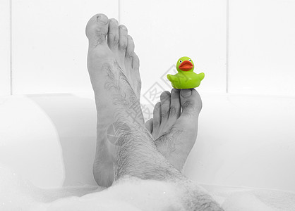 男人脚在浴缸里 有选择性地关注脚趾肥皂浴室塑料鸭子小鸭子漂浮橡皮童年玩具乐趣图片