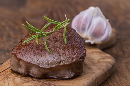 剪切板上的烤牛排炙烤迷迭香牛肉烧烤香料木头食物红色鱼片桌子图片