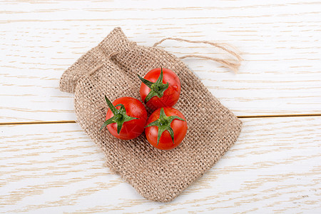 小麻袋和红发红熟 美味的新鲜樱桃番茄叶子花园营养生长食物饮食生产植物蔬菜西红柿图片