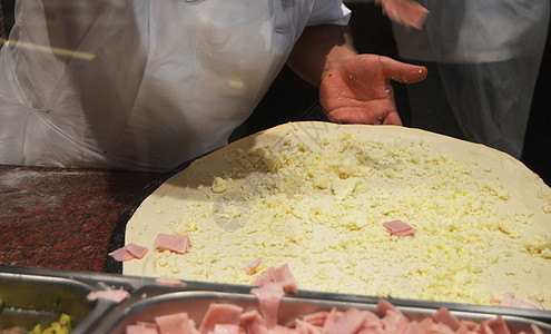 穿白色围裙的厨师做一个大披萨 特写了比萨配料火 芝士 黑暗背景咖啡店食物桌子男性烹饪工作烤箱美食餐厅火腿图片