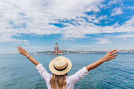 在土耳其伊斯坦布尔的一个热门景点上站立和观望着美丽的女人的背影天空火鸡旅游景观旅行少女们游客女性享受帽子图片