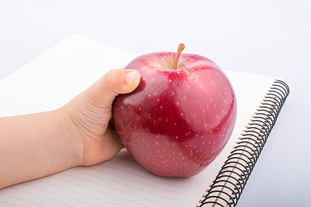 手拿着笔记本上的红苹果学校水果日记字帖商业教科书饮食教育笔记床单图片