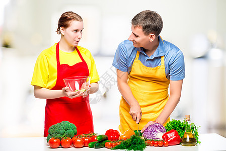 在厨房准备健康蔬菜沙拉的年轻夫妇在厨房里图片