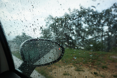 大雨从车挡风玻璃下流下来 汽车的景色是玻璃交通雨滴镜子窗户蓝色天气城市路口街道图片