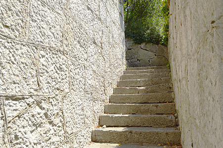 旧的狭窄楼梯 两边都有石墙 上面有石墙 阳光照亮森林公园阴影途径旅游石头人行道小路建筑花园图片