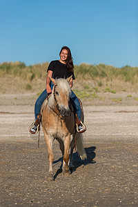 女孩骑着马在沙滩上沙丘海滩马匹小矮人动物骑术哺乳动物马术自由青少年图片